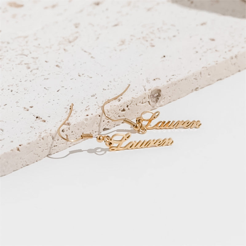 Close up photo of custom gold dangle earrings from custom name jewelry