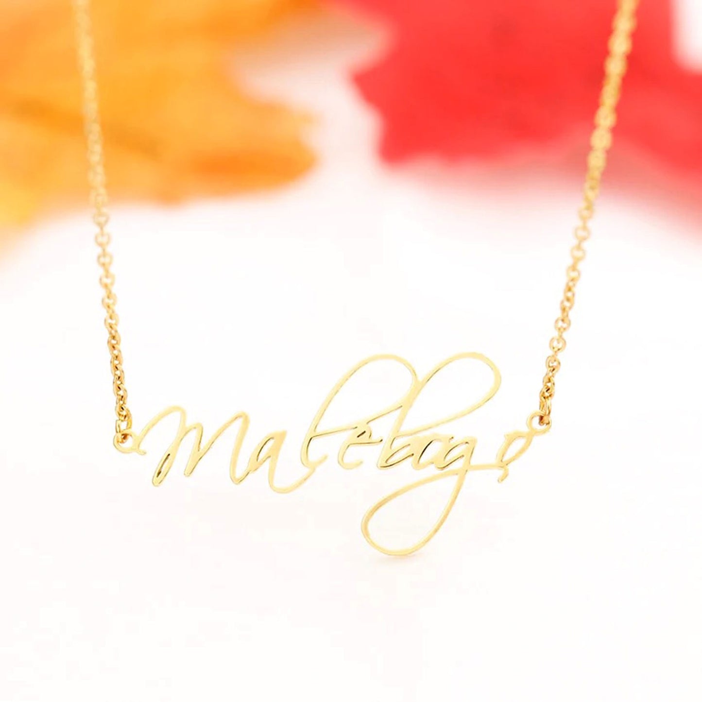 Detail of a gold-tone link chain and a personalized script name necklace.